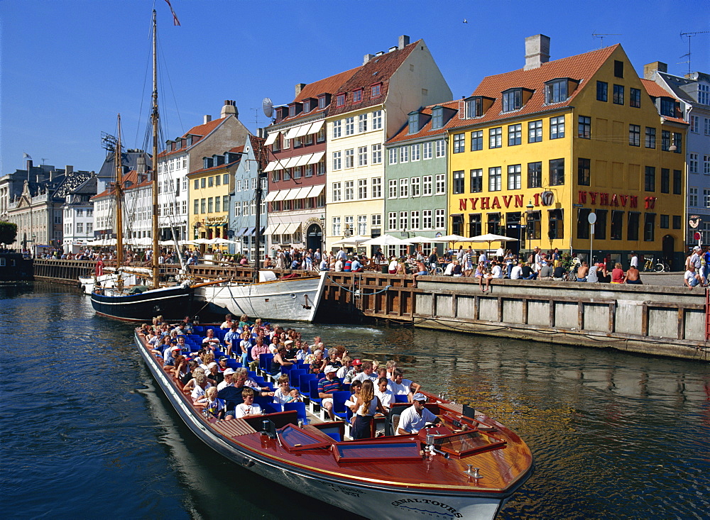 Tourists on boat trip pass painted buildings on the busy waterfront of Nyhavn, Copenhagen, Denmark, Scandinavia, Europe