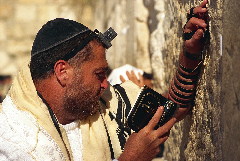 Close-up of Jew wearing shawl, skull cap and phylactery and holding a book, praying at the Western Wall in Jerusalem, Israel, Middle East