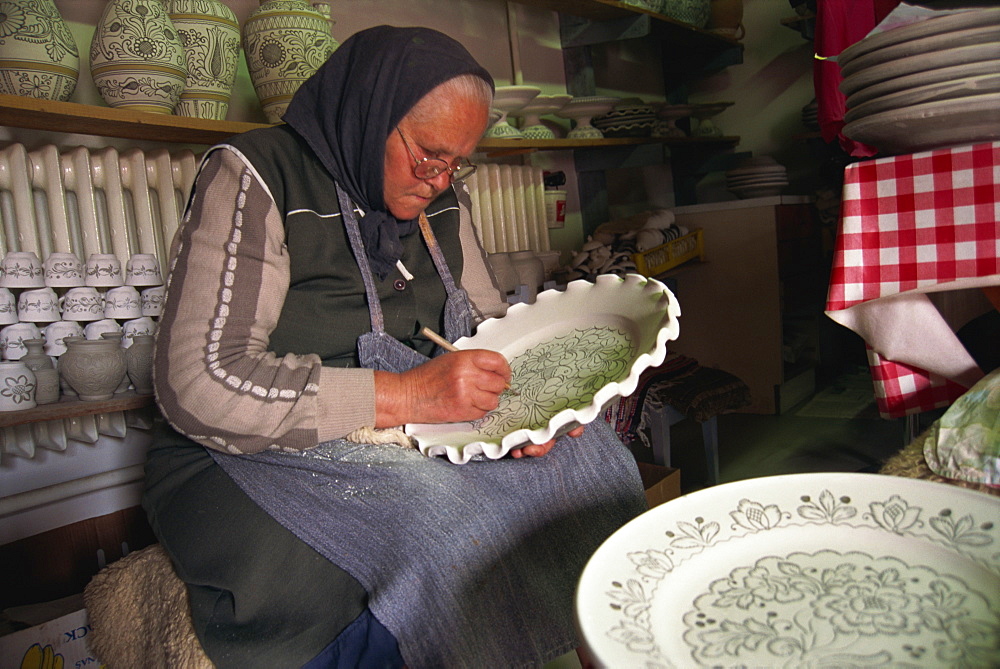 Woman drawing design on a plate in the ceramics workshop at Corund, Transylvania, Romania, Europe