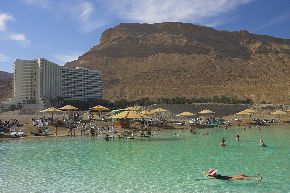 People floating in the sea and Hyatt hotel and desert cliffs in background, Ein Bokek Hotel Resort, Dead Sea, Israel, Middle East 