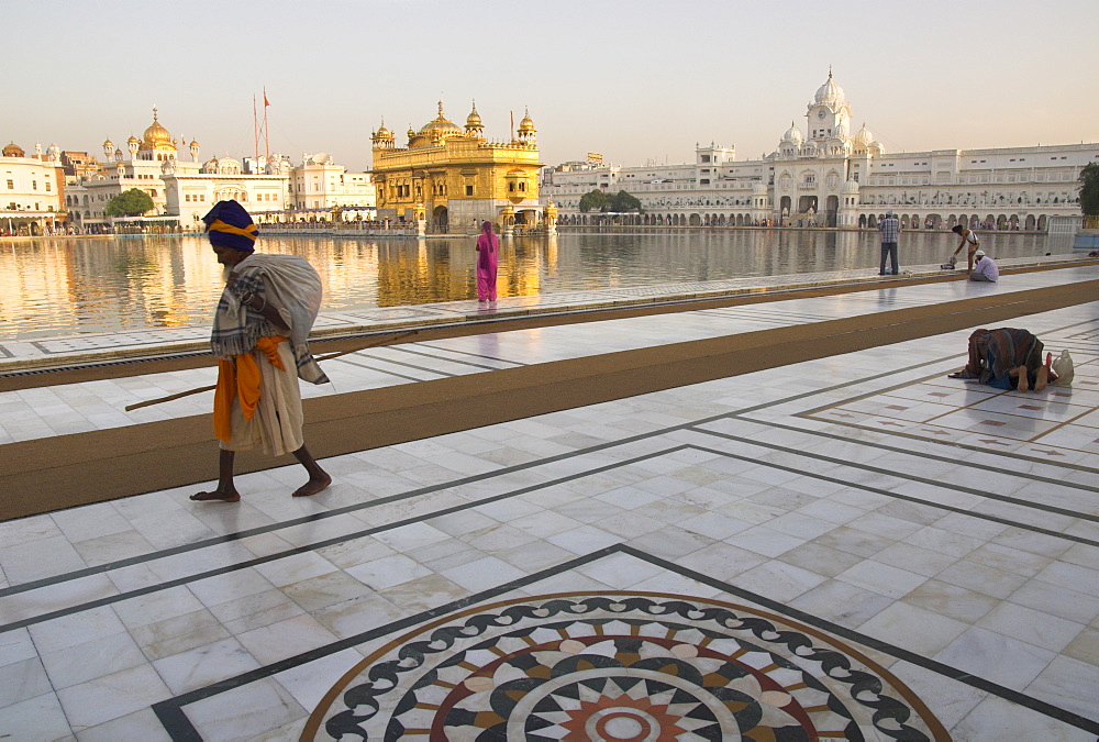 Elderly Sikh pilgrim with bundle and stick walking around holy pool, Golden Temple, Amritsar, Punjab state, India, Asia