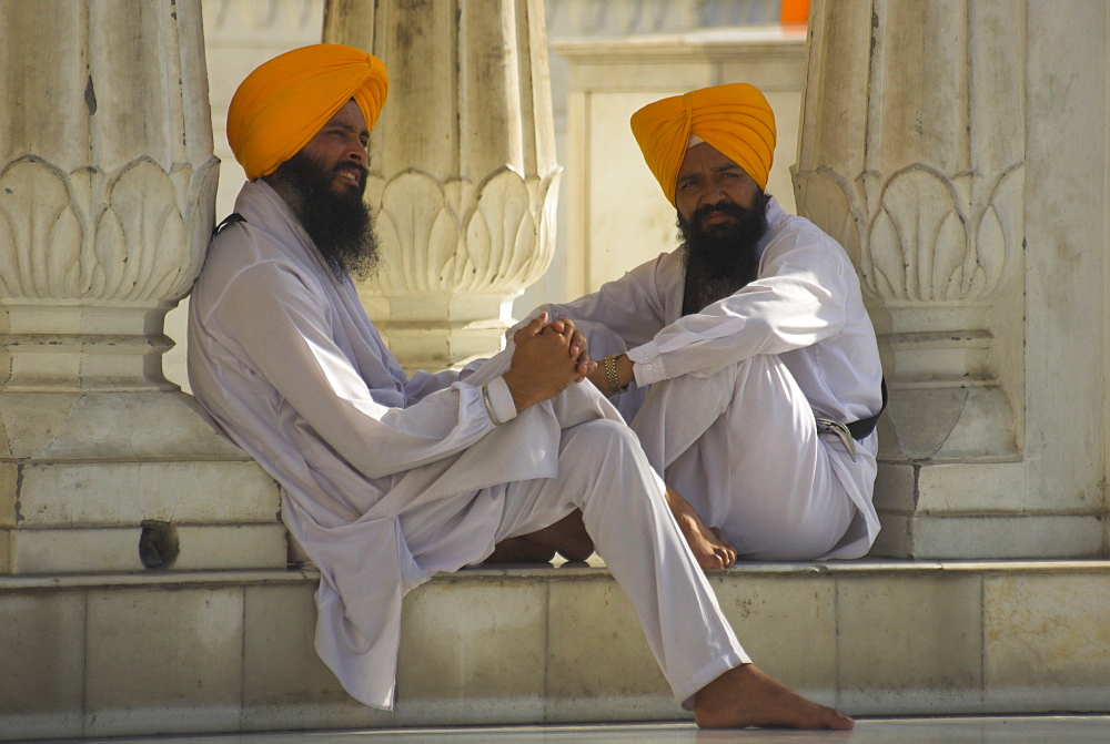 Two Sikhs priests with orange turbans, white dress and beards sitting under arcades, Golden Temple, Amritsar, Punjab state, India, Asia