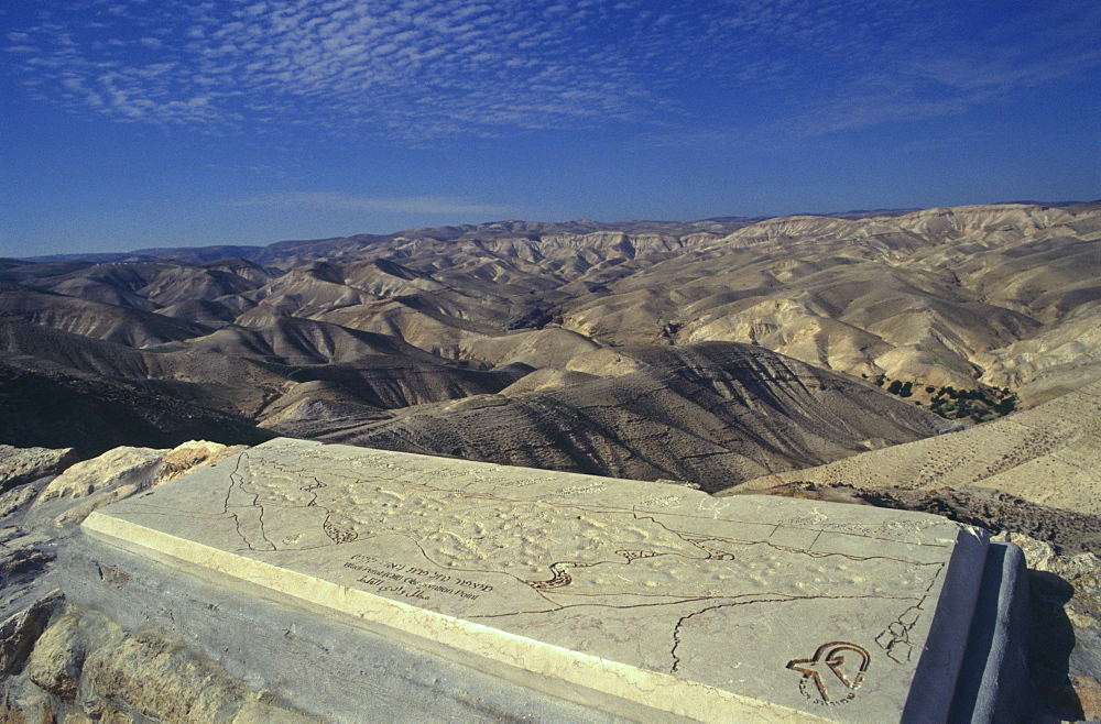 View from cliff with descriptive map carved on slab in foreground and hills beyond, Wadi Qelt, Judean Desert, Israel, Middle East