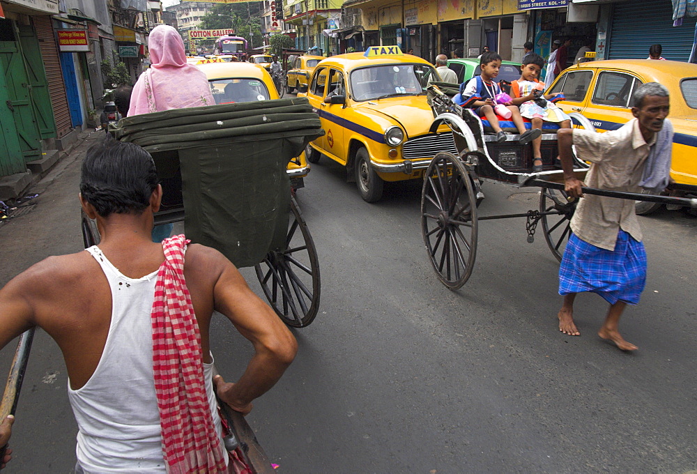 Hand pulled rickshaws and yellow taxis, Kolkata, West Bengal state, India, Asia