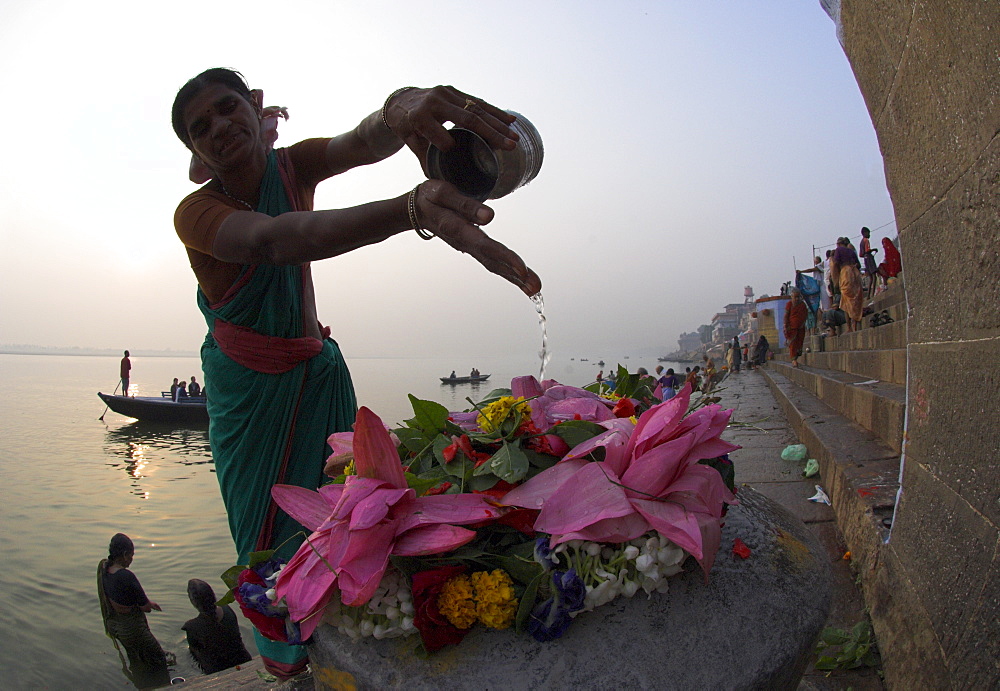 Woman pouring water over flowers on an altar as a religious ritual, Kedar Ghat, Varanasi, Uttar Pradesh state, India, Asia