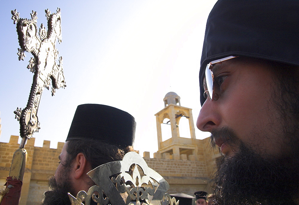 Close up of two Orthodox priests holding a metal cross in front of St. John monastery during ceremony at Epiphany, Qasr el Yahud, Israel, Middle East