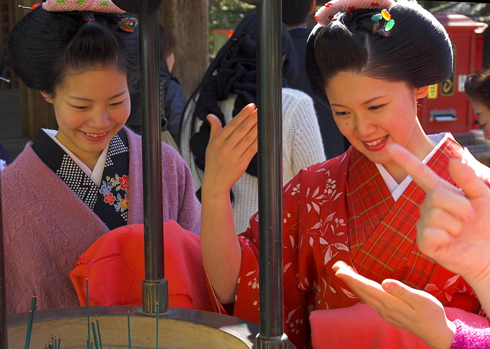 Two maikos blessing themselves in front of burning incense at temple, Golden Pavilion, Rokuon ji temple, Kinkaku ji, Kyoto, Kansai, Honshu, Japan, Asia