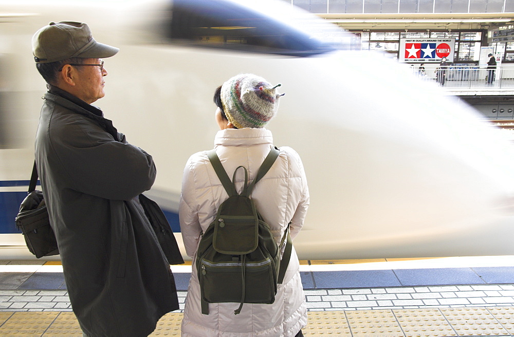 Couple waiting on platform with train arriving, Shizuoka Shinkansen train station, Honshu, Japan, Asia