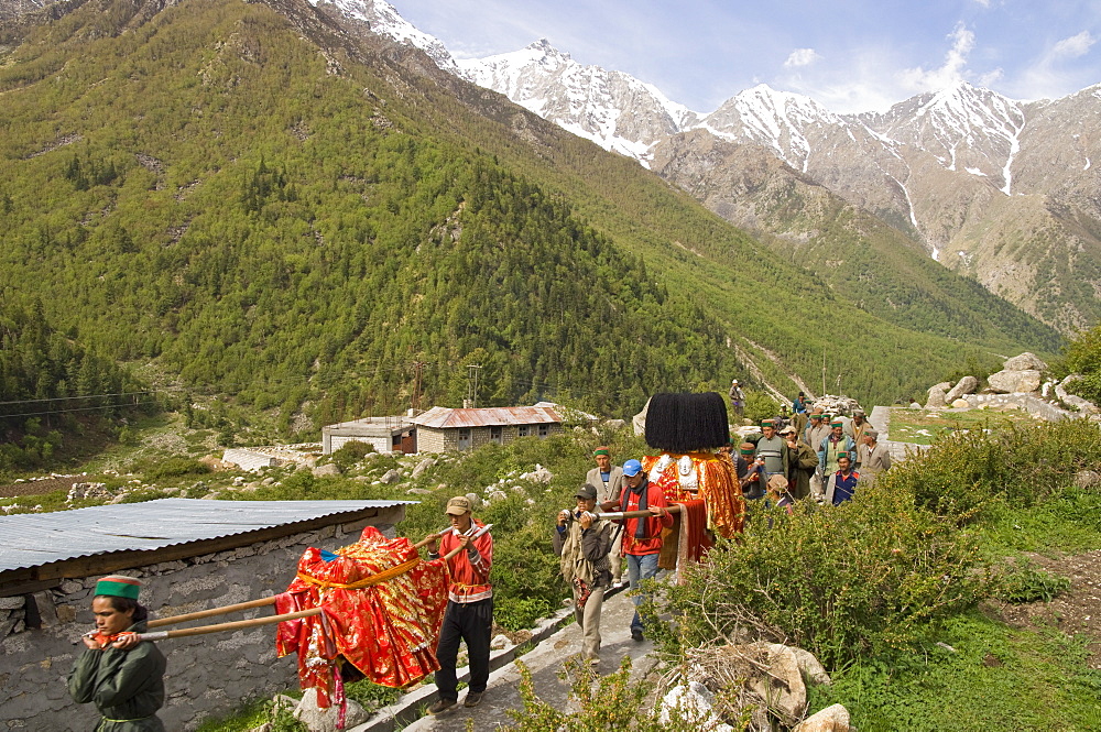 Daily religious puja procession with local deities in the valley with snowy mountain tops in background, Chitkul, 3460m, Baspa Valley, Kinnaur, Himachal Pradesh, India, Asia