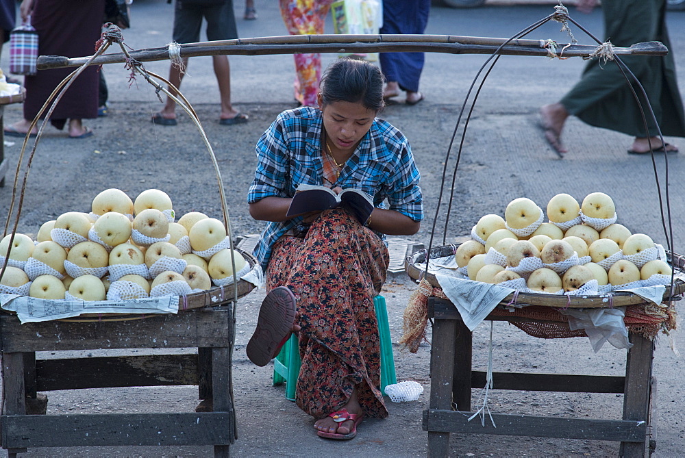 Young woman selling apples from a portable stall in the streets of Yangon (Rangoon), Myanmar (Burma), Asia