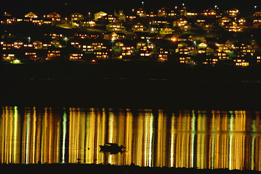 Lights of Tromso reflected off the sea at night, Arctic Norway, Scandinavia, Europe