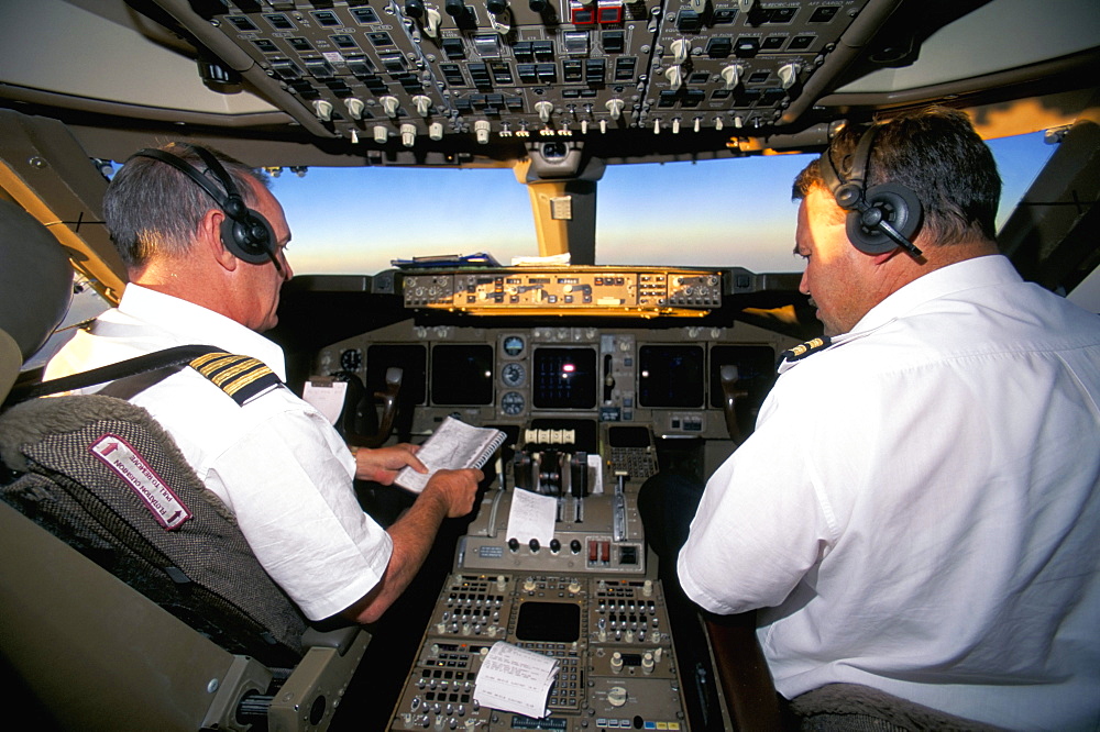 Pilots on flight deck of Jumbo Boeing 747 of Air New Zealand with sunrise ahead