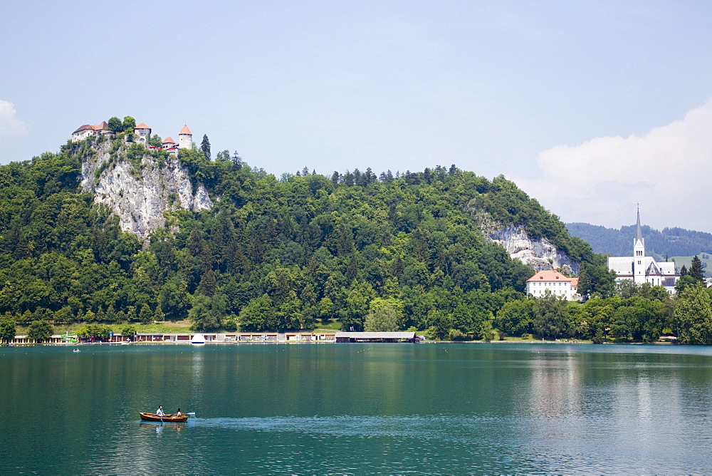 Traditional wooden pletnja (rowing boat) to ferry tourists to St. Mary's Church of Assumption on the islet beyond, Lake Bled, Slovenia, Europe