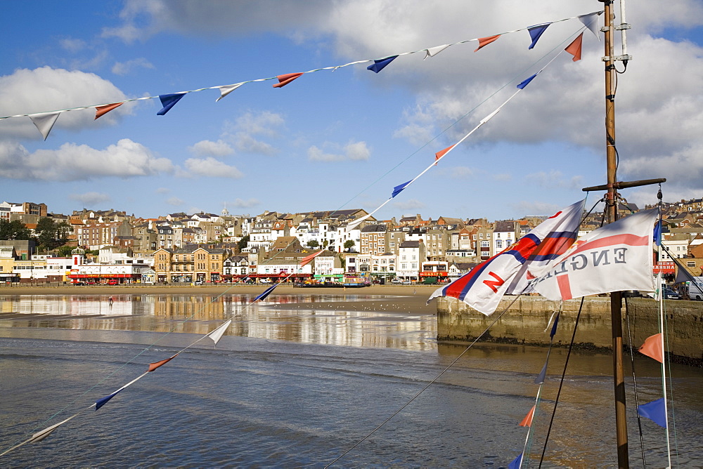 England flag on boat mast in South Bay, with South Sands beach and seafront beyond, Scarborough, North Yorkshire, England, United Kingdom, Europe