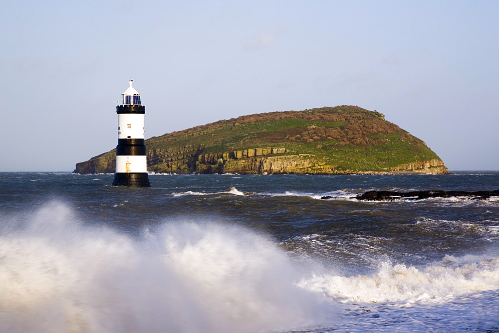 Penmon Point Lighthouse, built in 1838 at the northern entrance to the Menai Strait, and Puffin Island, with rough sea at high tide in winter, Penmon, Anglesey, Wales, United Kingdom, Europe