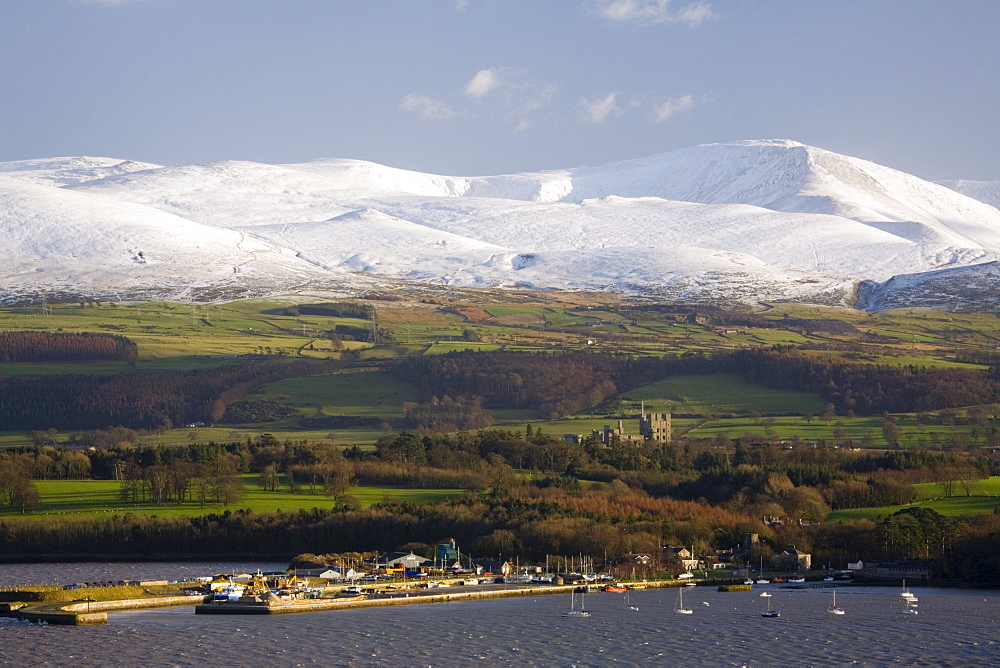 Bangor Port and Penrhyn Castle from across the Menai Strait with snow on mountains of Snowdonia National Park beyond in winter, Menai Bridge, Anglesey, North Wales, United Kingdom, Europe