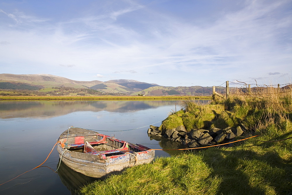 Scenic view with old rowing boat moored on bank in calm water on River Dovey (Afon Dyfi) looking north in low winter sunlight, Glandyfi, Ceredigion, Dyfed, Wales, United Kingdom, Europe