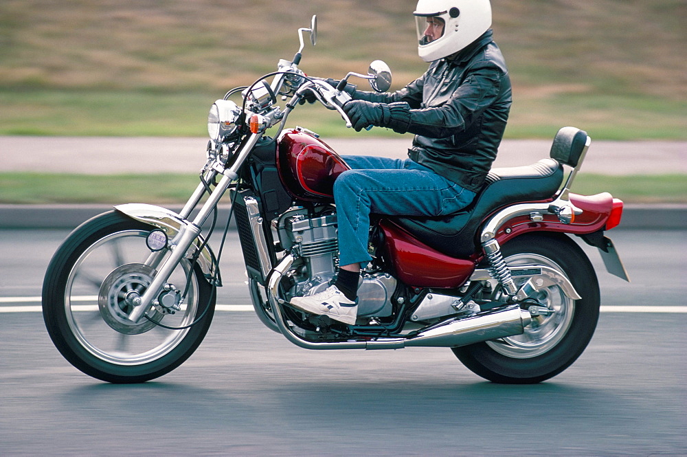 Motorcyclist rides Suzuki twin motorcycle on highway, Dawlish, Devon, England, United Kingdom, Europe