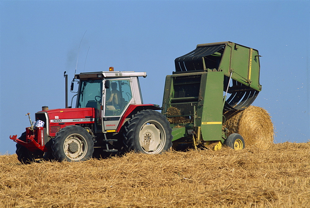 Tractor towing baler unloading drum bale, Wannock, Sussex, England, United Kingdom, Europe