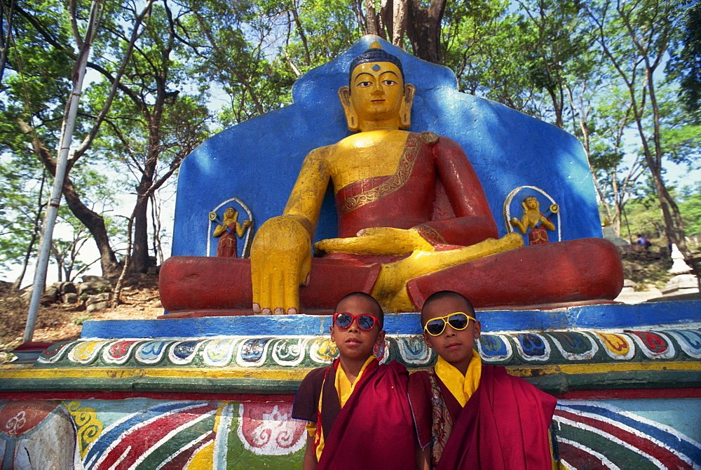 Thupten's twin monks, wearing sunglasses in front of a statue of the Buddha, outdoors, at the Swayambunath Stupa in Kathmandu, Nepal, Asia