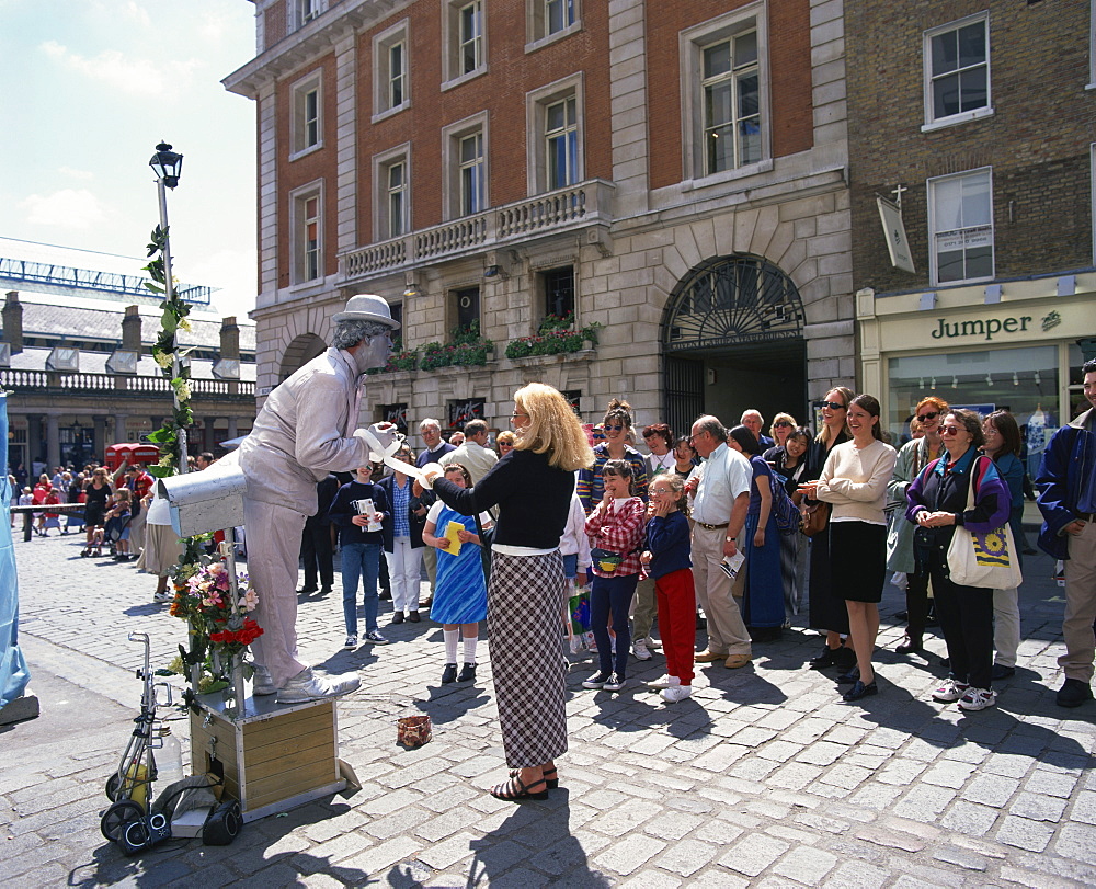 Statue street performer, and group of people watching, Covent Garden, London, England, United Kingdom, Europe