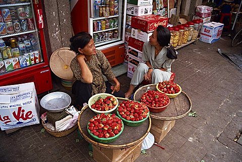 Two women street vendors selling strawberries on the pavement in Ho Chi Minh City (Saigon) in Vietnam, Indochina, Southeast Asia, Asia