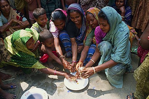 A group of Bangladeshi women and children washing hands as part of a health education scheme in Bangladesh, Asia