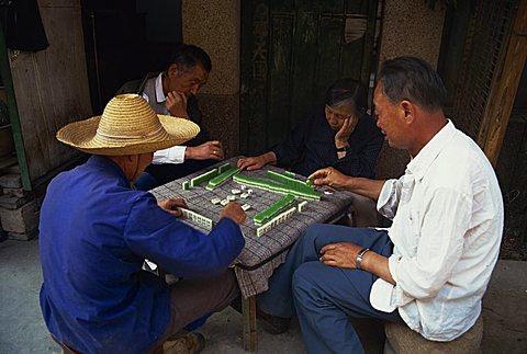 Portrait of a group of four men sitting at a table, playing a game of Mahjong, Yunnan Province, China, Asia