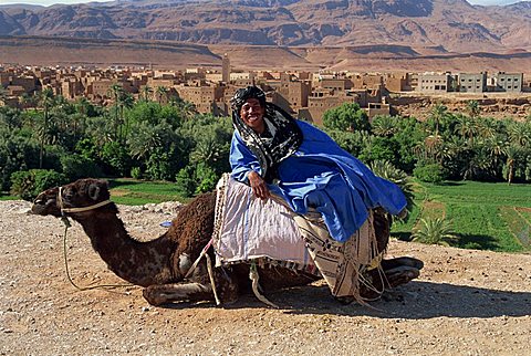 Portrait of a young man resting on camel, smiling and looking at the camera, near Todra Gorge, Tinerhir, Morocco, North Africa, Africa