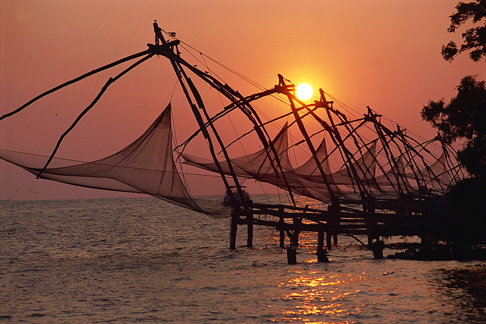 A line of Chinese fishing nets on the coast at sunset, Fort Cochin, Kerala, India, Asia