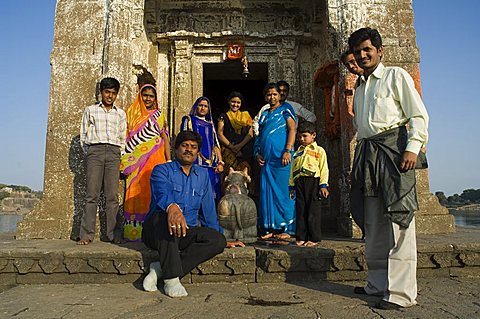 Family makes a visit to small Hindu temple in middle of the Narmada River, Maheshwar, Madhya Pradesh, India