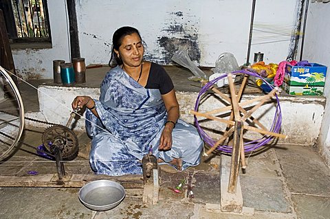 A woman spinning at one of the cooperatives in an area that is famous for its saris, Maheshwar, Madhya Pradesh state, India, Asia