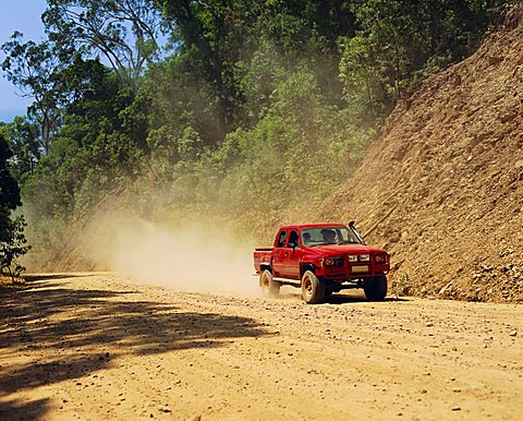 A red 4x4 pick-up on the dusty Bloomfield Track, Cape Tribulation National Park, Queensland, Australia