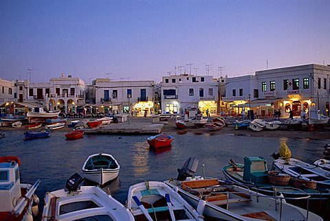 Boats in harbour at dusk, with shops and restaurants of Mykonos Town in the background, Cyclades Islands, Greece