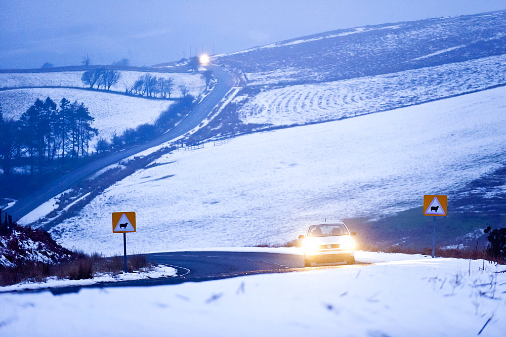 A motorist drives through a wintry landscape on the B4520, Brecon Road, on the Mynydd Epynt moorland, Powys, Wales, United Kingdom, Europe