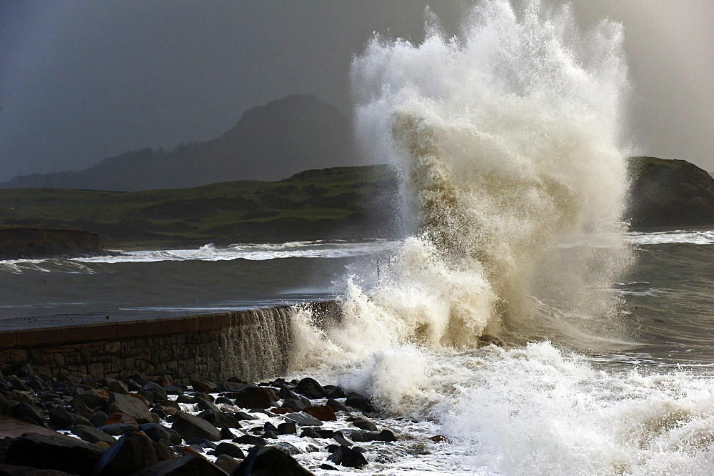 Huge waves crash against a stone jetty at Criccieth, Gwynedd, Wales, United Kingdom, Europe