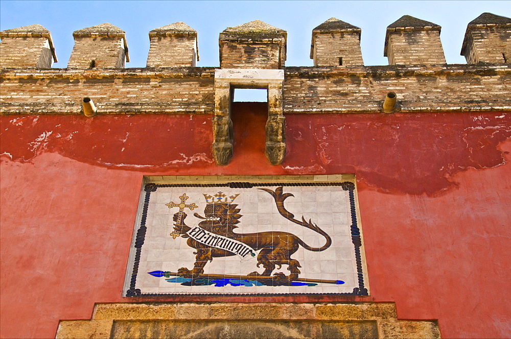 Royal lion emblem fresco and fortifications above entrance of the Alcazar, Seville, Andalusia, Spain, Europe