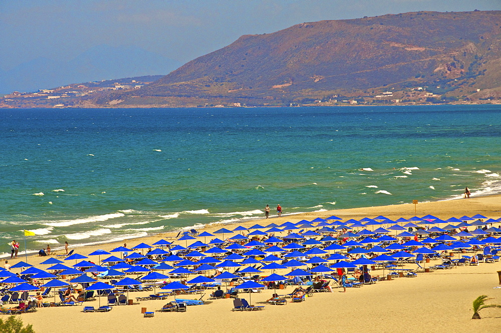 Beach and blue sunshades on beach at Giorgioupolis, with mountain in the background, Crete, Greek Islands, Greece, Europe