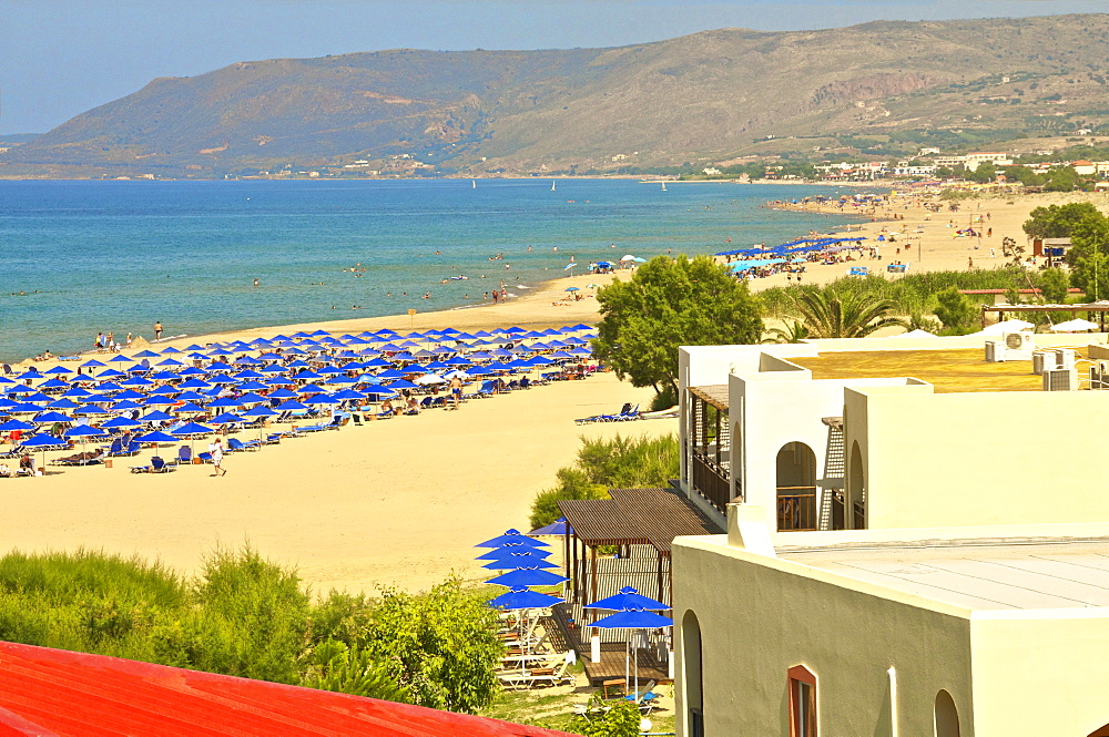 Beach and blue sunshades on beach at Giorgioupolis, with mountain in the background, Crete, Greek Islands, Greece, Europe