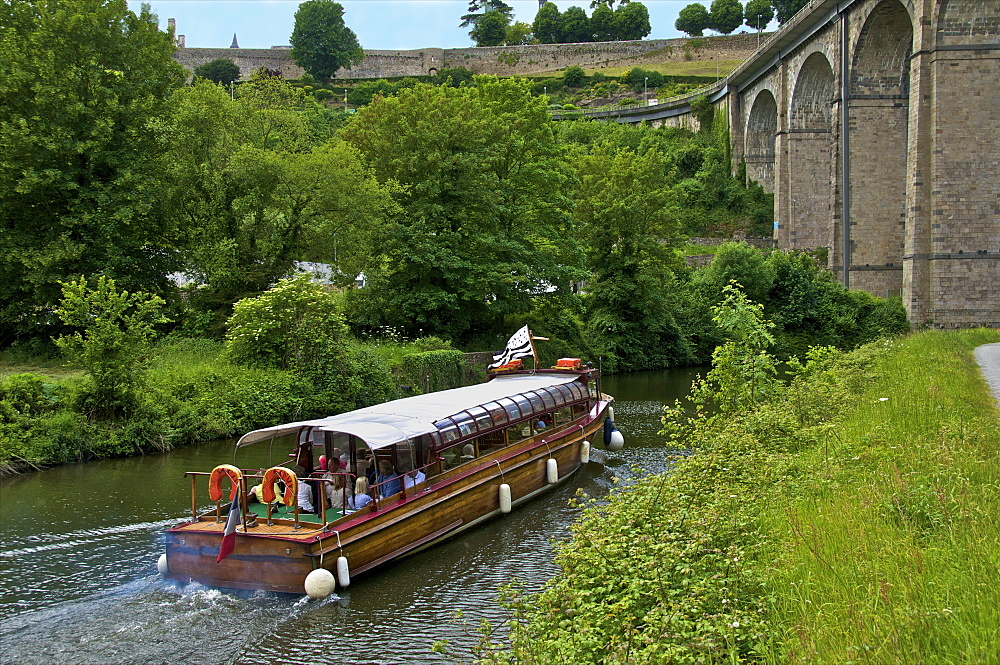 Tourists boat on river Rance, and river banks, with aqueduct, and castle walls, Dinan, Brittany, France, Europe