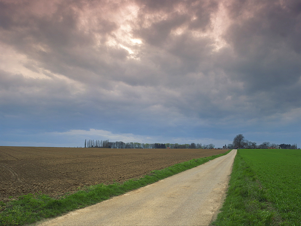 Overcast sky and rural road through fields in agricultural landscape near Entrepagny, Normandy Vexin, Basse Normandie (Normandy), France, Europe