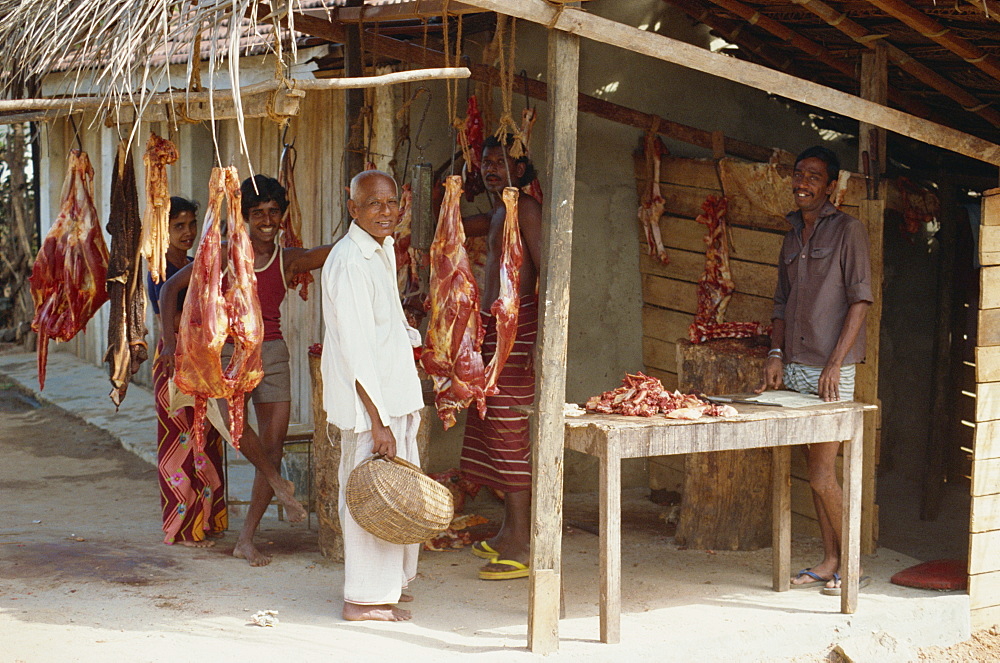 Meat for sale at a butchers stall, and Sri Lankan men looking at the camera, near Colombo, Sri Lanka, Asia