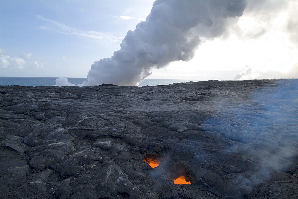 Skylight, view through cooled lava to molten lava below, with plumes of steam as lava reaches the sea beyond, Kilauea Volcano, Hawaii Volcanoes National Park, UNESCO World Heritage Site, Island of Hawaii (Big Island', Hawaii, United States of America, North America