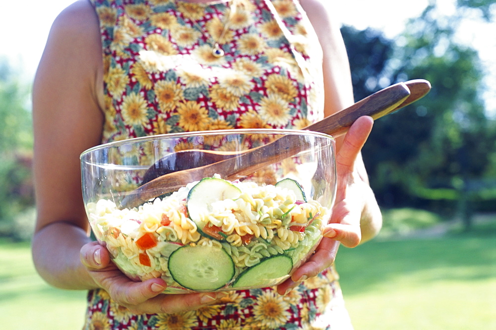 Woman holding a large bowl of pasta salad