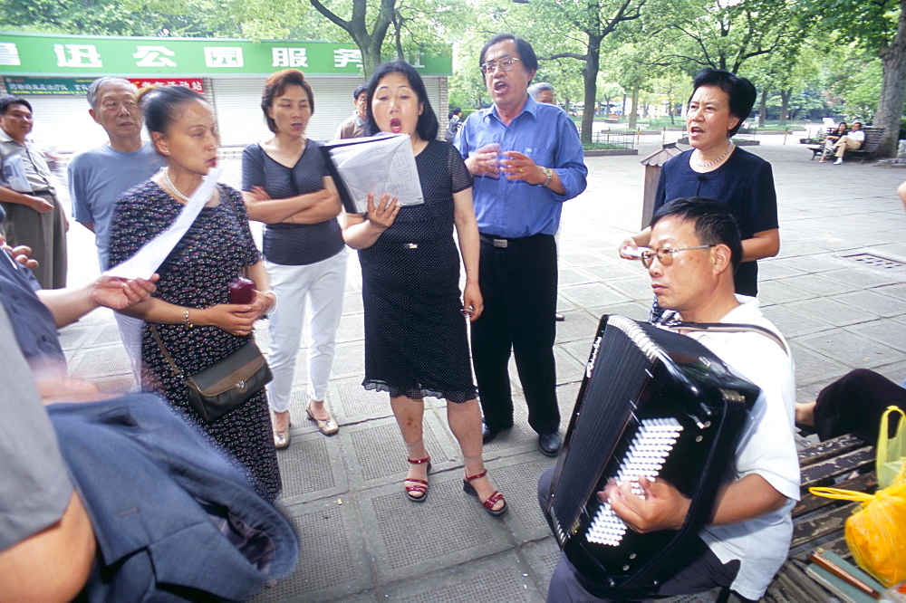 Group of people singing to accordian music, Shanghai, China, Asia