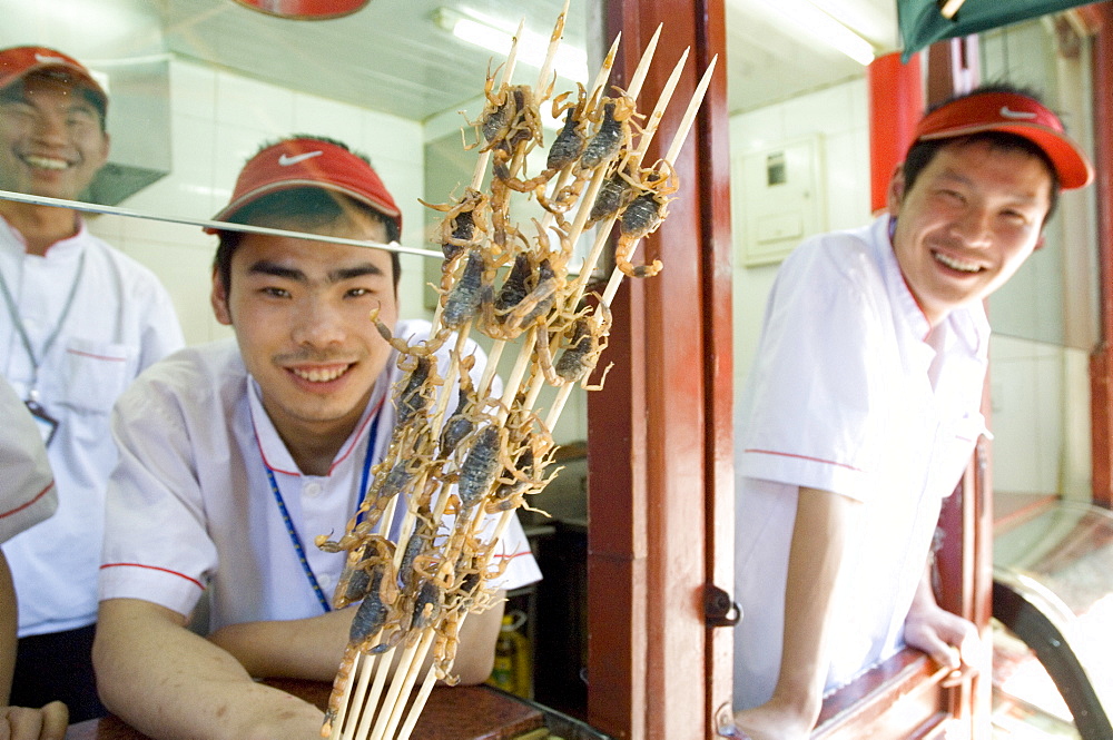 Eating a snack of skewers of scorpion at a hutong near Wang Fu Jing road, where grasshopper, sea horse, snakes, larva and starfish also served, Beijing, China, Asia