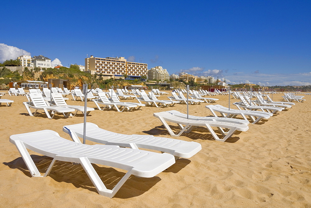 Empty white sun lounger sunbeds on Praia da Rocha beach, Portimao, Algarve, Portugal, Europe