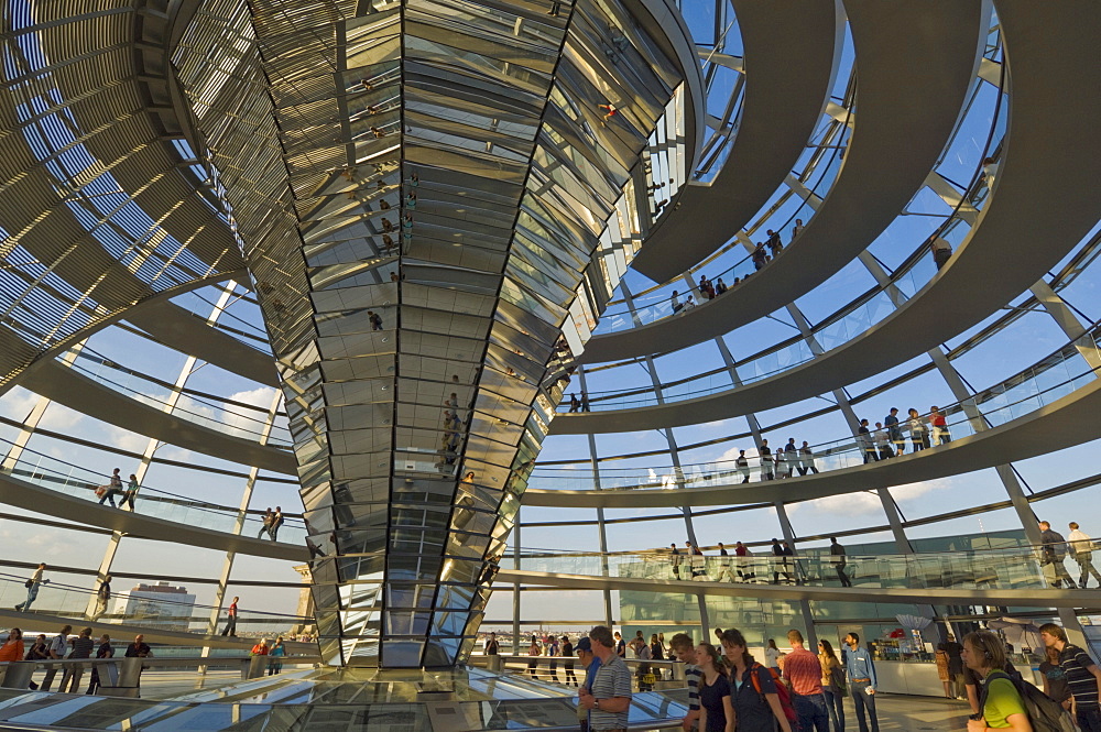 Visitors walk up a spiralling ramp around the cone shaped funnel in the dome cupola, which has 360 glass mirrors reflecting light into the Plenary chamber of the Reichstag building, designed by Sir Norman Foster, Berlin, Germany, Europe