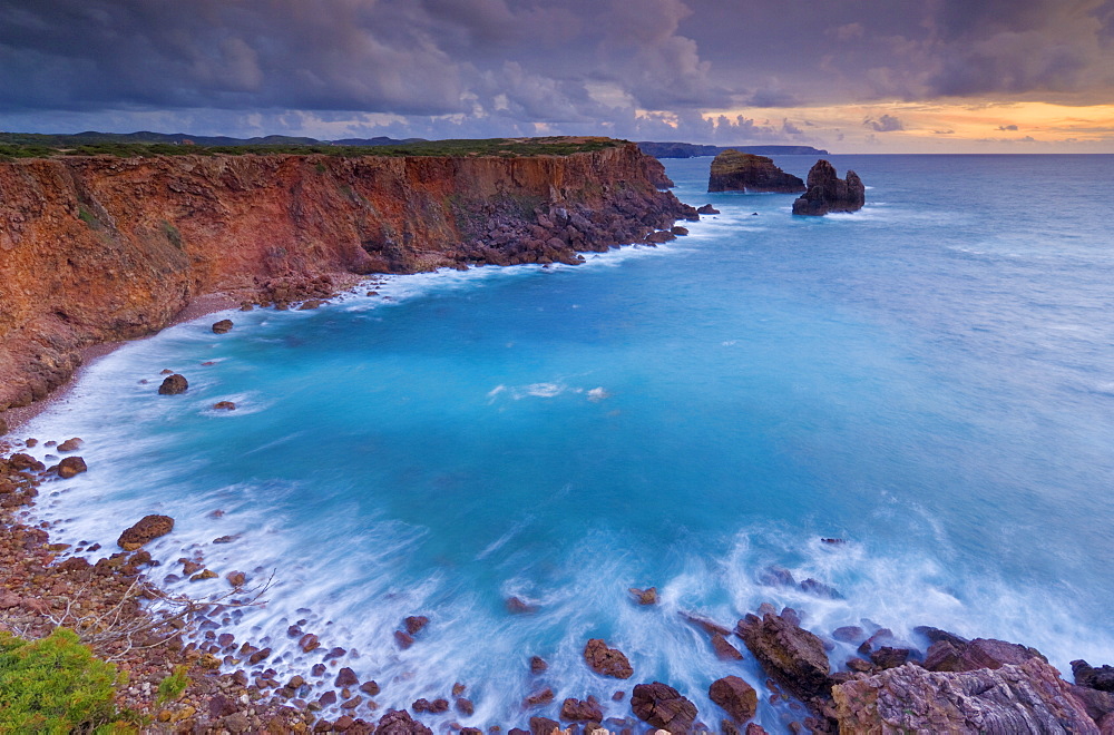 Stormy sunset sky with milky tide and surf taken on a slow shutter speed, Costa Vincente, Atlantic coast of Algarve, Portugal