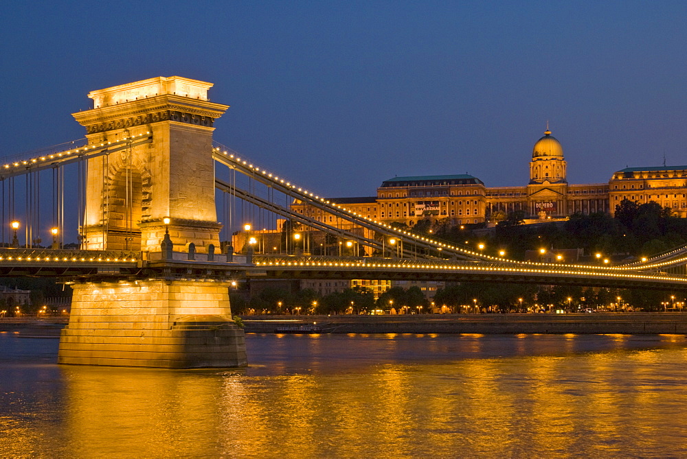 The Chain Bridge (Szechenyi Lanchid), over the River Danube, illuminated at sunset with the Hungarian National Gallery also lit, behind, Budapest, Hungary, Europe